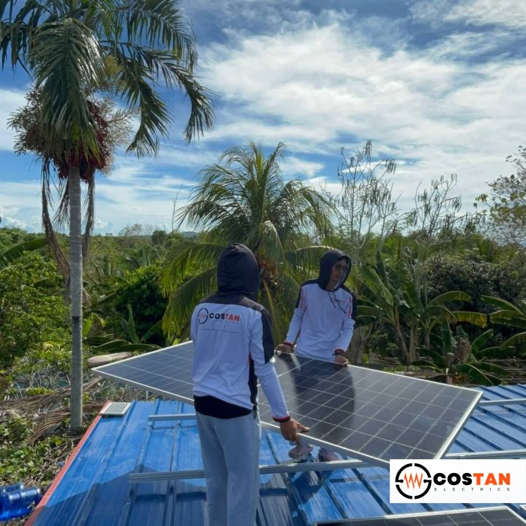 Costan Electrics solar installers carrying and positioning a photovoltaic panel on a rooftop in San Jose, Getafe, Bohol